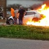 Hulpmannen trekken vrouw uit brandende auto